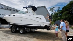 Carter Mitchell scampers aboard his family's new boat, Friday, July 24, 2020, in Yarmouth, Maine. Across the country boat dealers are reporting more sales as people cannot travel during the pandemic. (AP Photo/Robert F. Bukaty)