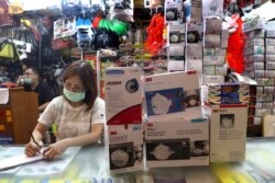 Seorang penjaga toko duduk di dekat kotak-kotak masker yang dijajakan di sebuah toko di Jakarta (2 Maret 2020).
