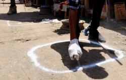 A worker marks a social distancing sign as a preventive measure against the spread of the coronavirus disease (COVID-19), at the market centre in Hamarweyne district in Mogadishu, Somalia, April 16, 2020.