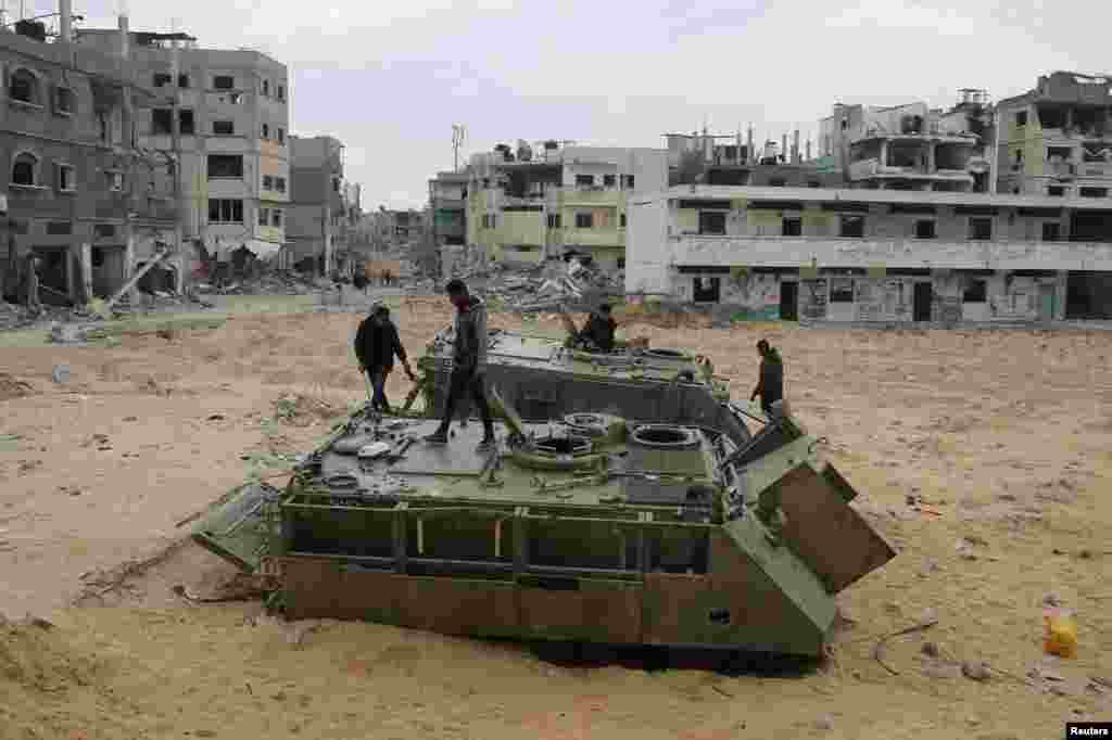 Palestinians look at damaged Israeli military vehicles left behind by Israeli forces, following a ceasefire between Israel and Hamas, in Rafah in the southern Gaza Strip.