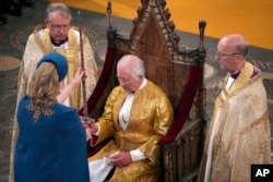 La Lord presidenta del Consejo, Penny Mordaunt, presenta la Espada del Estado al Rey Carlos III durante su ceremonia de coronación, en Londres, el sábado 6 de mayo de 2023. (Aaron Chown/ vía AP)