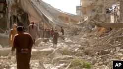 This undated frame grab from video posted online May 29, 2017, by the Aamaq News Agency, a media arm of the Islamic State group, shows people inspecting damage from airstrikes and artillery shelling in the northern Syrian city of Raqqa.
