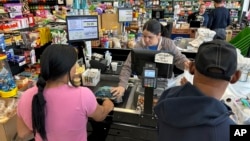 ARCHIVO - La cajera Rosa Dilone ayuda a los clientes en el supermercado Mi Tierra en Hazleton, Pensilvania, el 16 de mayo de 2024.