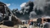 People are seen in front of clouds of black smoke from fires in the aftermath at the scene of an airstrike in Mekele, the capital of the Tigray region of northern Ethiopia, Oct. 20, 2021. 