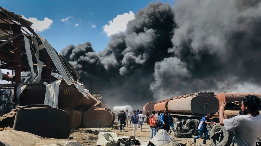 People are seen in front of clouds of black smoke from fires in the aftermath at the scene of an airstrike in Mekele, the capital of the Tigray region of northern Ethiopia, Oct. 20, 2021. 