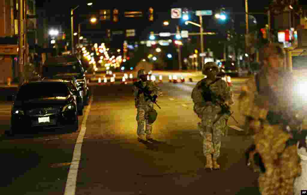 Para anggota pasukan Garda Nasional berjalan sepanjang North Avenue di Baltimore dekat tempat kerusuhan Senin menyusul pemakaman Freddie Gray, setelah jam malam pukul 10 berlaku Rabu (29/4).&nbsp;​(AP/David Goldman)