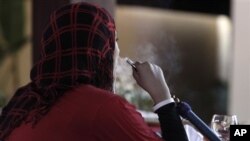 FILE - A Palestinian woman smokes a water pipe at a cafe in Gaza City, July 18, 2010. 