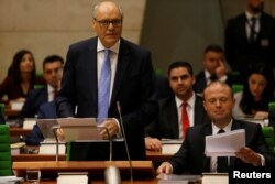 FILE - Maltese Finance Minister Edward Scicluna, flanked by Prime Minister Joseph Muscat, presents his government's 2019 budget at parliament in Valletta, Malta, Oct. 22, 2018.