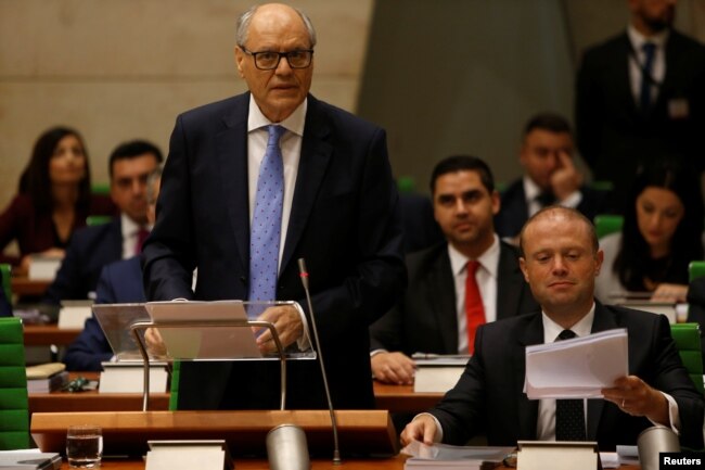FILE - Maltese Finance Minister Edward Scicluna, flanked by Prime Minister Joseph Muscat, presents his government's 2019 budget at parliament in Valletta, Malta, Oct. 22, 2018.