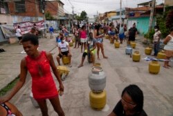 People wait with their empty canisters to buy low cost cooking gas sold by the Petrobras Oil Tankers Union in the Vila Vintem favela of Rio de Janeiro, Brazil, Oct. 28, 2021.