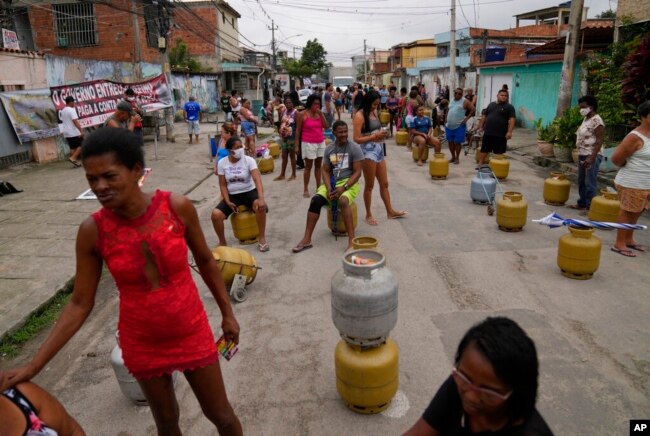 People wait with their empty canisters to buy low cost cooking gas sold by the Petrobras Oil Tankers Union in the Vila Vintem favela of Rio de Janeiro, Brazil, Oct. 28, 2021.