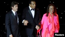 Mohamed Ali es acompañado por su esposa Lonnie Ali y un asistente, durante una presentación en Arizona, en 2013. 