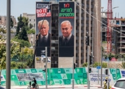 FILE - A man cycles past giant posters of U.S. President Donald Trump and Israeli Prime Minister Benjamin Netanyahu hanging on the facade of a building in Jerusalem, June 10, 2020.