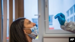 A medical student takes a nose swab sample for the novel coronavirus COVID-19 in Budapest, Hungary, Nov. 30, 2020.