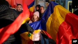 Un niño sentado entre banderas rumanas antes de un discurso de George Simion, líder de la Alianza para la Unidad de los Rumanos (AUR) después del cierre de las urnas durante las elecciones parlamentarias del país, en Bucarest, Rumania, el domingo 1 de diciembre de 2024. AP