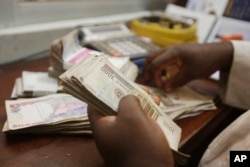 FILE - A money changer counts Nigerian naira currency at a bureau de change in Lagos, Nigeria.