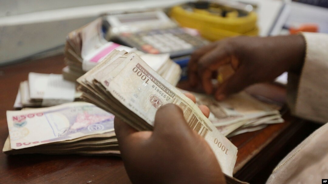 Seorang pegawai pertukaran uang menghitung mata uang naira di Lagos, Nigeria.