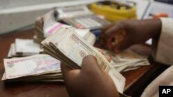 Seorang pegawai pertukaran uang menghitung mata uang naira di Lagos, Nigeria.