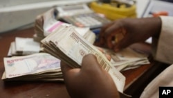 FILE - a money changer counts Nigerian naira currency at a bureau de change in Lagos, Nigeria, Oct. 20, 2015.