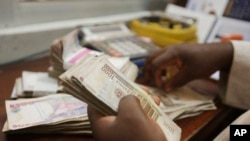 FILE - a money changer counts Nigerian naira currency at a bureau de change in Lagos, Nigeria, Oct. 20, 2015.