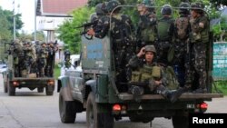 Government soldiers are seen onboard military vehicles driving along the main road of Amai Pakpak as the assault continues against insurgents from the Maute group, who have taken over large parts of Marawi City, Philippines, June 13, 2017. 