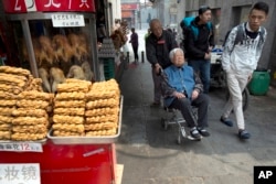 In this April 13, 2016 photo, shoppers past by traditional food on sale in Beijing. China's economic growth slowed in the first quarter to 6.7 percent compared with the previous year, according to official data released on April 15, 2016.