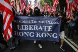 Protesters hold a banner and wave U.S. flags as they march to the U.S. consulate in Hong Kong, Sept. 8, 2019, seeking international support for their demands.