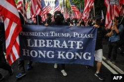 Protesters hold a banner and wave U.S. flags as they march from Chater Garden to the U.S. consulate in Hong Kong, Sept. 8, 2019, seeking international support for their demands.