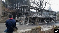 A man looks at the remains of a burned coach after a wild fire in Pontevedra, in the northwestern Spanish region of Galicia, Spain, Oct. 16, 2017. 
