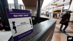 FILE - A sign advises travelers to keep their distance in Denver International Airport as travelers deal with the spread of coronavirus, March 20, 2020, in Denver. 
