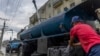 Un conductor de un camión cisterna se lava las manos mientras rellena su camión con agua para transportarla a edificios en medio de la escasez de agua en La Habana, Cuba, el 24 de septiembre de 2024.