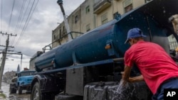 Un conductor de un camión cisterna se lava las manos mientras rellena su camión con agua para transportarla a edificios en medio de la escasez de agua en La Habana, Cuba, el 24 de septiembre de 2024.