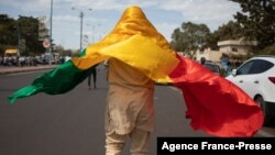 Un homme portant sur lui le drapeau malien lors d’une manifestation à Bamako contre les sanctions imposées au Mali et à la junte par la Cédéao, 14 janvier 2022.