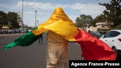 Un homme avec le drapeau national malien se joint à une manifestation de masse à Bamako, le 14 janvier 2022, pour protester contre les sanctions imposées au Mali et à la junte par la Cédéao.