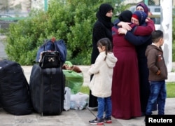 A Syrian refugee girl stands near luggage of Syrian refugees returning to Syria, in Beirut, Lebanon, Dec. 6, 2018.