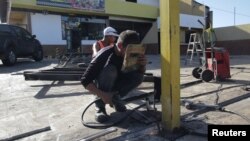 Workers repair the fence of a supermarket, after it was looted in Puerto Ordaz, Venezuela, Jan. 9, 2018. 