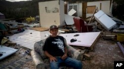 Luis Cosme poses sitting in an armchair in what is left of his house destroyed by Hurricane Maria, in Morovis, Puerto Rico, Oct. 1, 2017. 