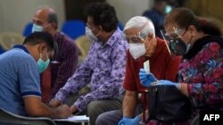 A medical worker gathers information from senior citizens waiting to get the Covid-19 in Karachi on March 16, 2021. (Photo by Asif HASSAN / AFP)