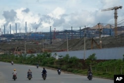 Motorists ride past Indonesia Weda Bay Industrial Park's compound in Central Halmahera, North Maluku, Indonesia, Saturday, June 8, 2024. Indonesia has been building out a vast industry for nickel. (AP Photo/Achmad Ibrahim)