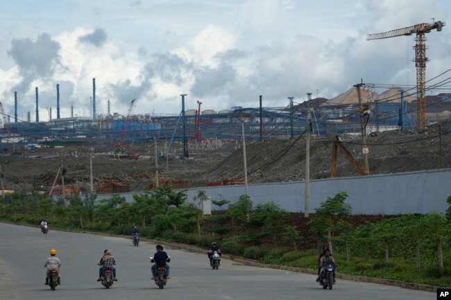 Motorists ride past Indonesia Weda Bay Industrial Park's compound in Central Halmahera, North Maluku, Indonesia, Saturday, June 8, 2024. Indonesia has been building out a vast industry for nickel. (AP Photo/Achmad Ibrahim)