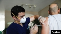 FILE - Ledsiel Garcia, a pharmacy technician with DeliveRxd Pharmacy in Tampa, administers the Pfizer-BioNTech vaccine to Mike Payne, a federal employee, at his home in St. Petersburg, Fla., July 30, 2021.