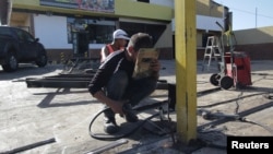 Workers repair the fence of a supermarket, after it was looted in Puerto Ordaz, Venezuela, Jan. 9, 2018. 