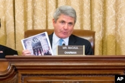 FILE - House Homeland Security Committee Chairman Michael McCaul, R-Texas, center, holds up a copy of Dabiq, the monthly online magazine used by the Islamic State group for propaganda and recruitment, on Capitol Hill in Washington, Oct. 21, 2015.