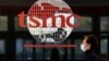 FILE - A man walks past signage at the headquarters of the semiconductor maker TSMC, in Hsinchu, Taiwan, Jan. 29, 2021. 