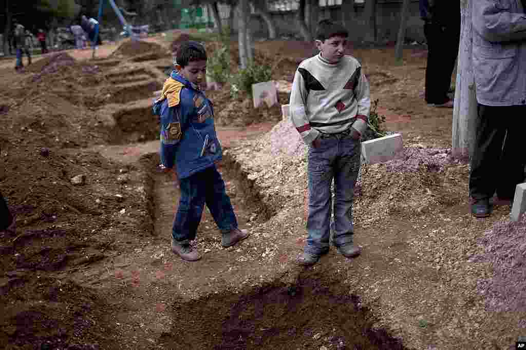 Children attend the funeral of a three Free Syrian Army fighters in a park converted to a cemetery in Idlib. (AP)