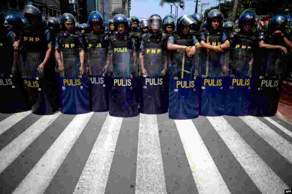Police officers in riot gear stand in formation as protesters attempt a march to the U.S. embassy in Manila, Philippines, during the 50th Association of Southeast Asian Nations (ASEAN) regional security forum.