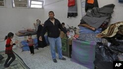Sufian Wadiya, 36, whose home was destroyed by Israeli strikes during last summer's Israel-Hamas war, stands in front of his 12-member family's belongings at a U.N. school in Gaza City where they now live, Jan. 27, 2015. 