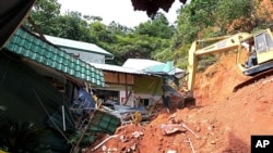 A rescuer uses a construction machine to search for the bodies believed to be buried by a landslide in Hulu Langat in central Selangor state, outside Kuala Lumpur, Malaysia, May 21, 2011.