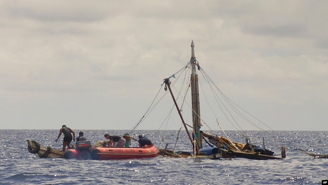 Anggota pasukan penjaga pantai Filipina (kiri) mendekati kapal nelayan yang hampir tenggelam, di perairan dekat kota Zamboanga, selatan Filipina, 10 Januari 2016. (Philippine Coast Guard via AP) 