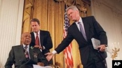 FILE - Then-President Bill Clinton and then-Vice President Al Gore, back, help Herman Shaw, 94, a Tuskegee syphilis study victim, during a news conference on May 16, 1997, when Clinton apologized to blacks whose syphilis went untreated by government doctors.